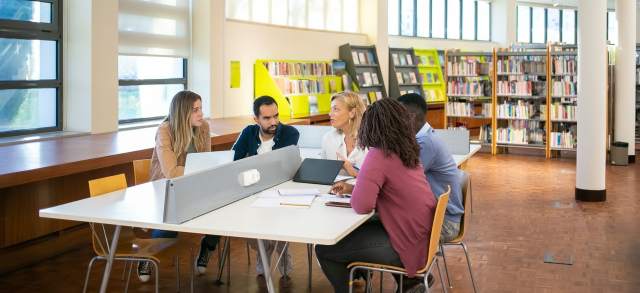 Bachelor-of-Arts-Studierende besprechen sich bei der Gruppenarbeit in der Bibliothek.