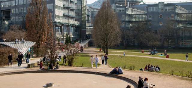 Moderner Hochschulcampus mit Studierenden im Park, wo sich duales und normales Studium unterscheiden lassen.