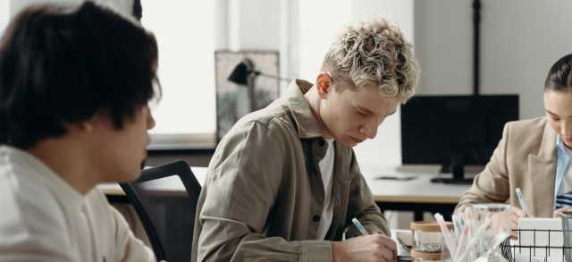 Praktikant*innen arbeiten im Büro an ihren Aufgaben.