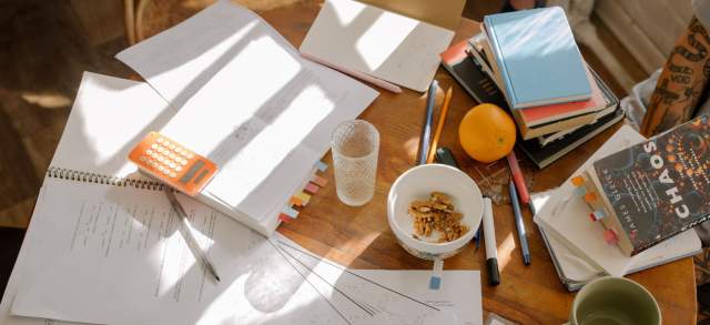 Studentin bereitet am Schreibtisch mit ihren Unterlagen das Semester vor.