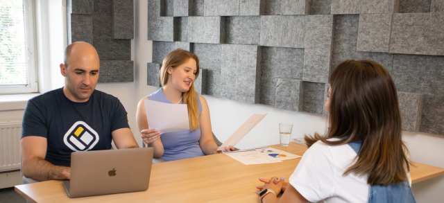 Drei Personen sitzen an einem Tisch im Gespräch und nutzen eine persönliche Studienberatung.