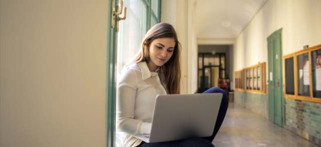 Studentin sitzt am Laptop und informiert sich über die Zulassung zum Studium.