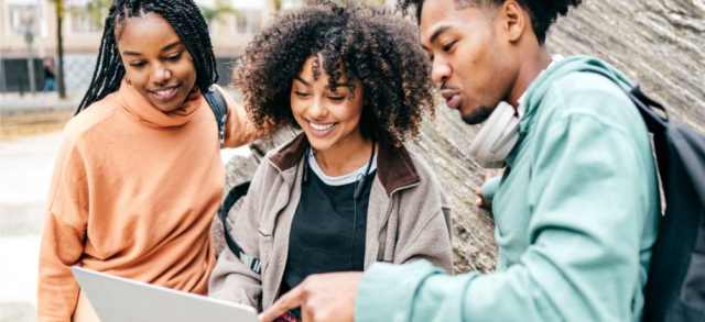 Three students looking at a laptop