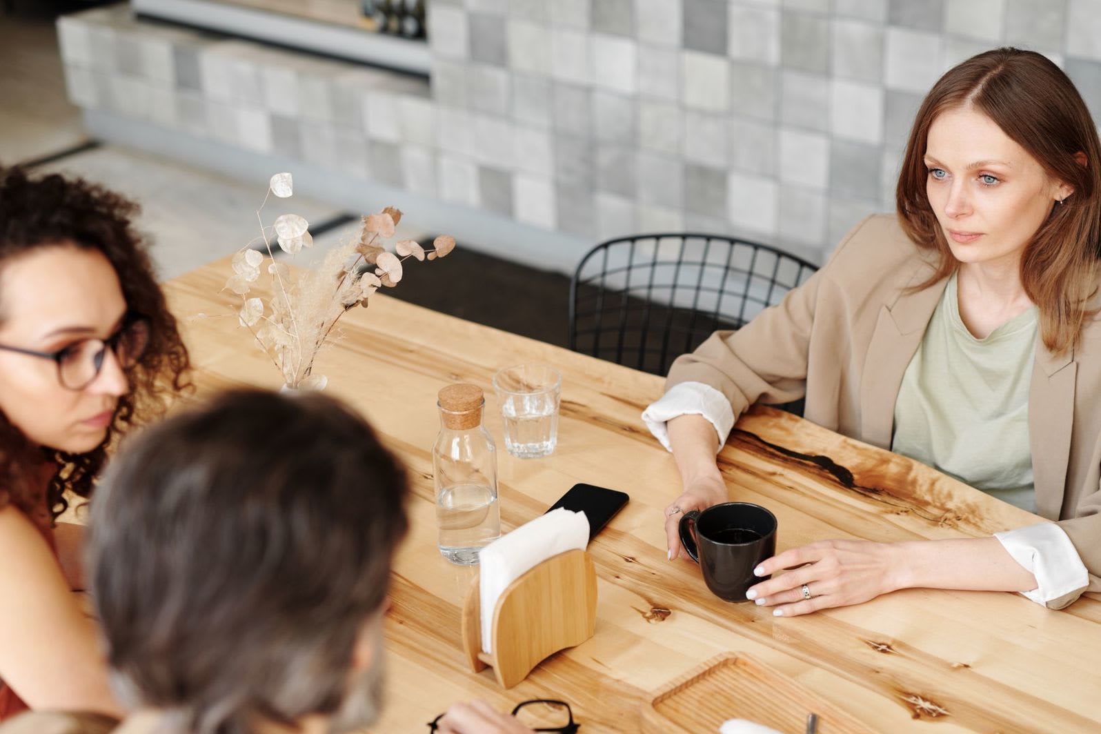 Ein Team bespricht bei Kaffee an einem Tisch aktuelle Projekte, wie es in der Marketingbranche zum Arbeitsalltag gehört.