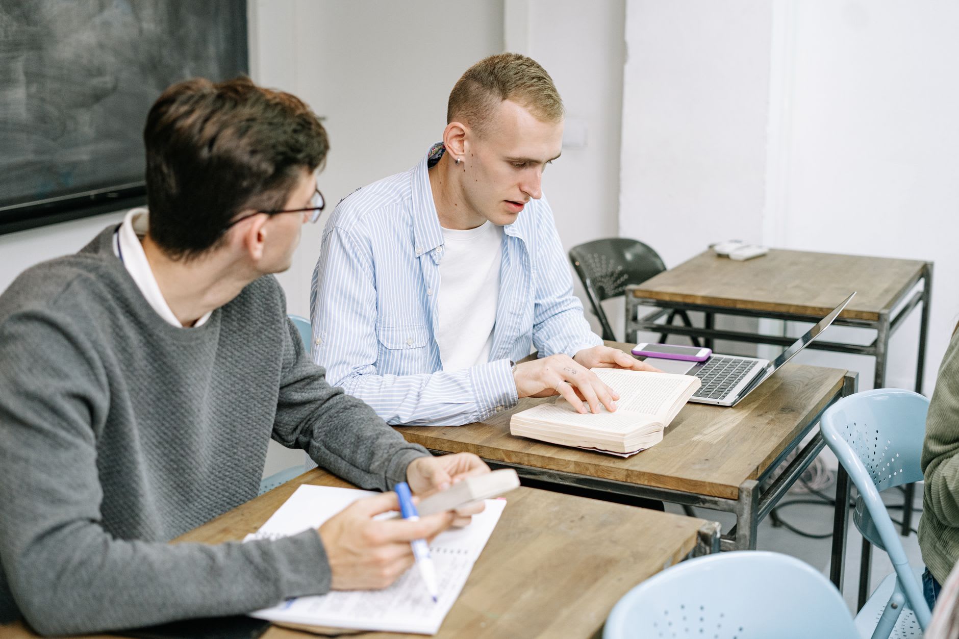 Zwei junge Männer lernen gemeinsam am Tisch zur Vorbereitung auf den Aufnahmetest.