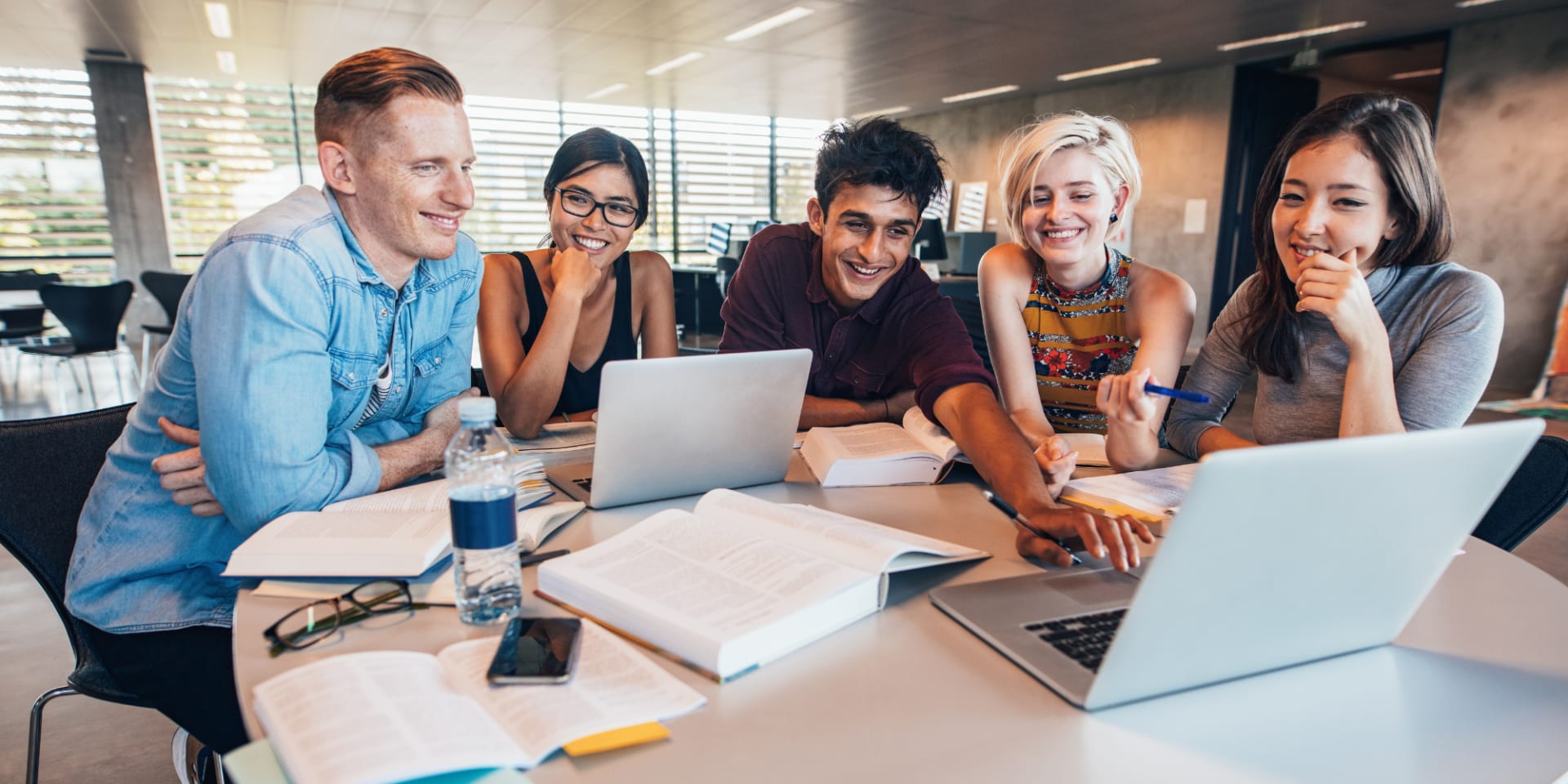 Junge MBA Student*innen arbeiten zusammen an einem Business-Projekt.