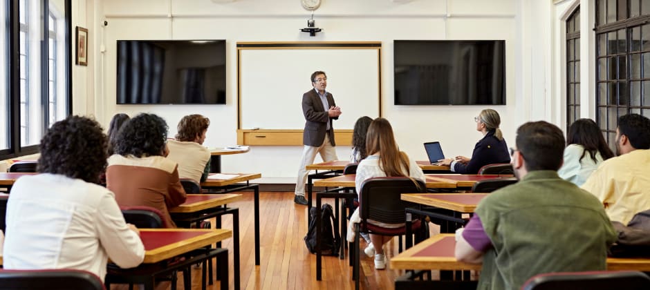 Student writing on glass board in classroom