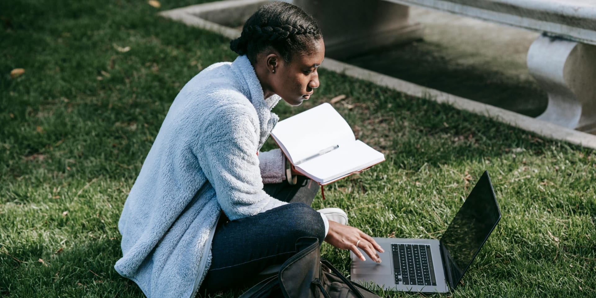 student sitting on the grass with a laptop