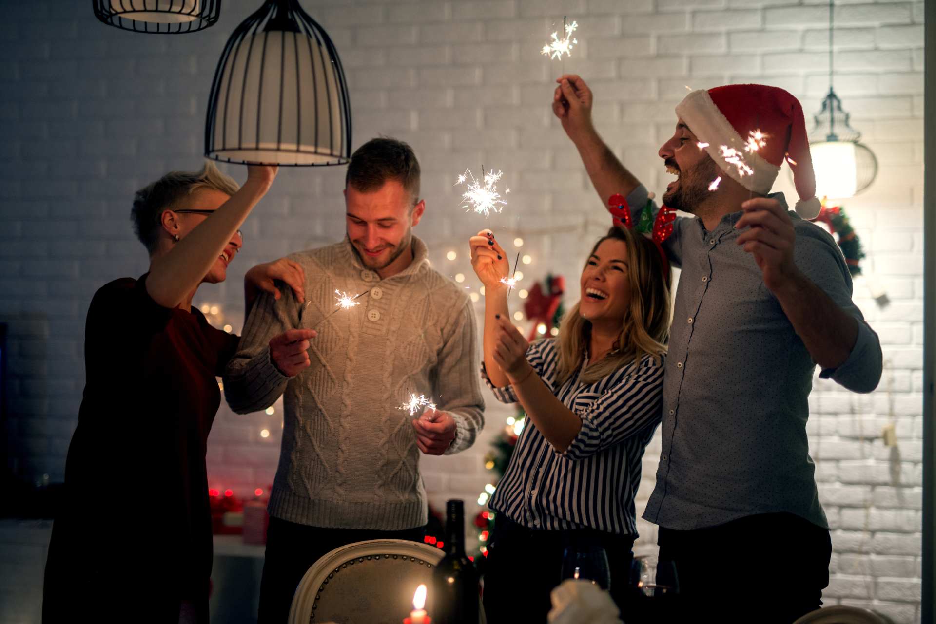 Group of smiling friend having fun with sparkles at home for Christmas in the night.