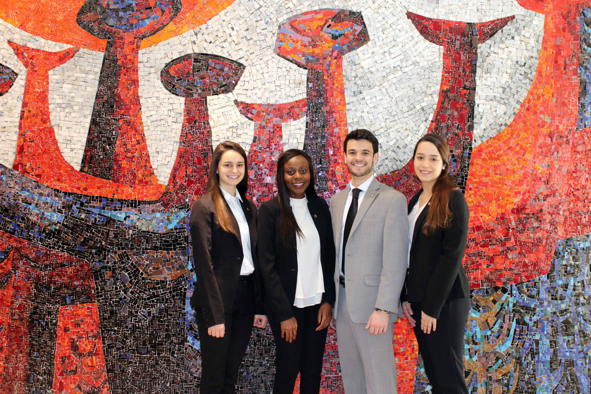 4 名穿着商务装的学生，在马赛克前