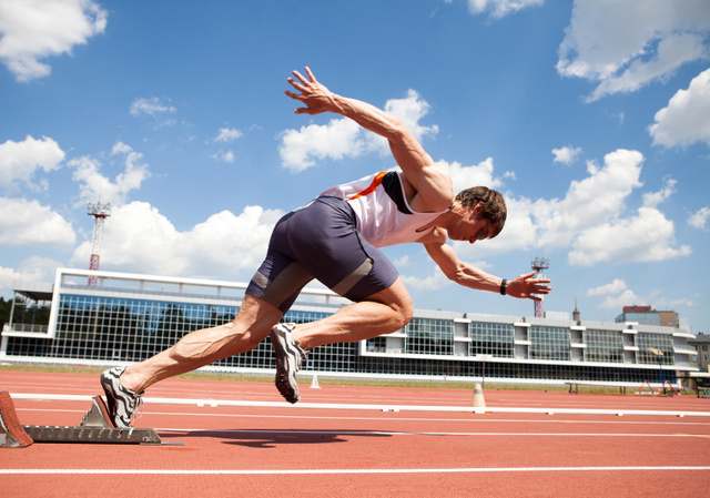 young muscular athlete is at the start of the treadmill at the stadium