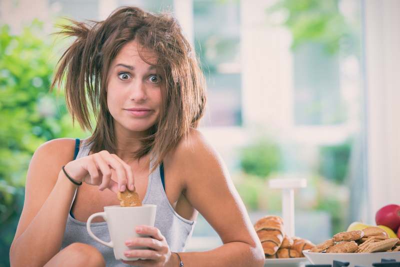 Young messy woman have breakfast in the kitchen