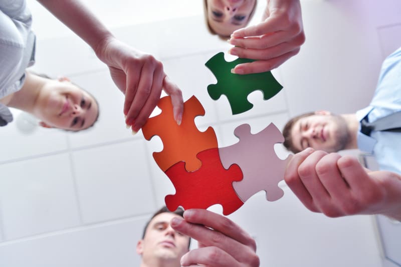 Group of business people assembling jigsaw puzzle and represent team support and help concept