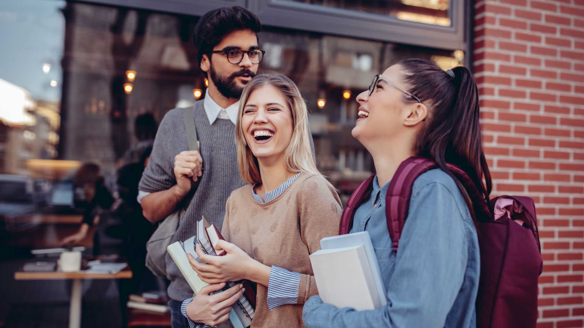 Three happy students talking on the street