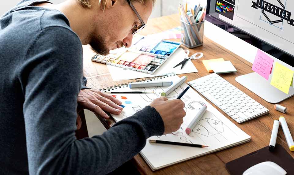 A graphic designer mocks up logo designs at his desk