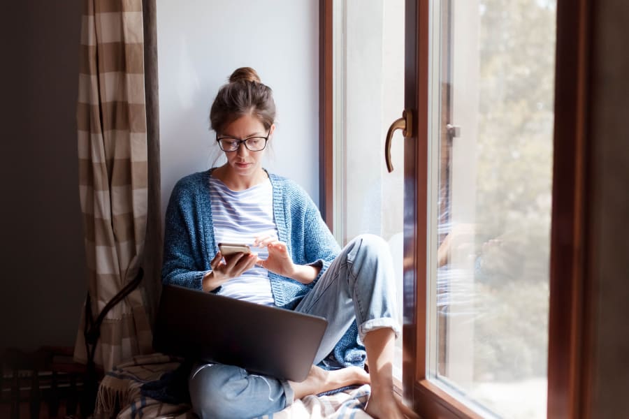 Young woman working from home office. Freelancer using laptop, phone and the Internet.
