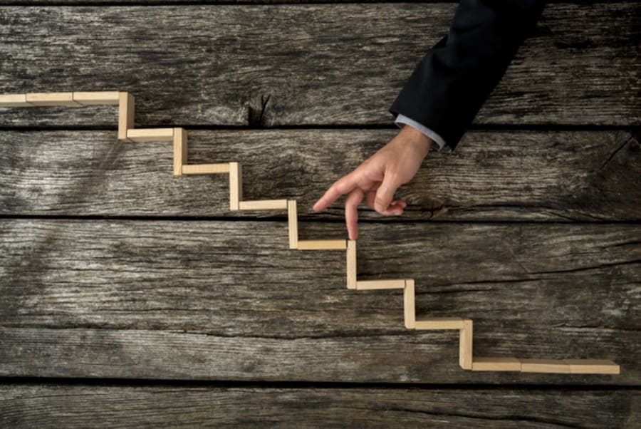 Businessman or student walking his fingers up wooden steps resembling a staircase mounted in rustic wooden boards in a conceptual image of personal and career development, success and aspiration.