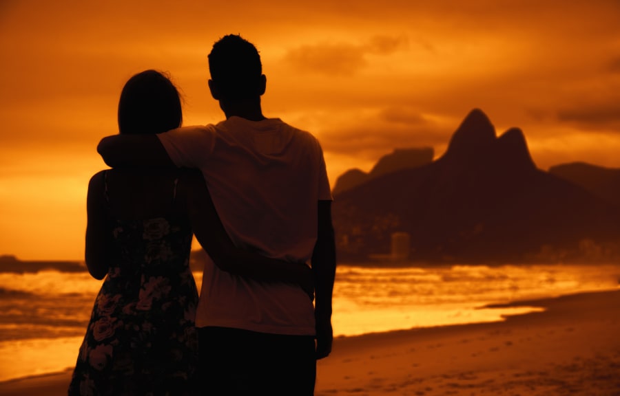Love couple in arms on beach at sunset at Rio