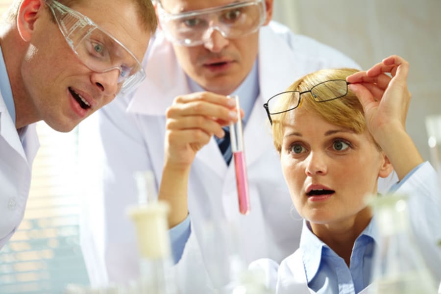 Three inspired scientists looking at a substance discovered in a lab