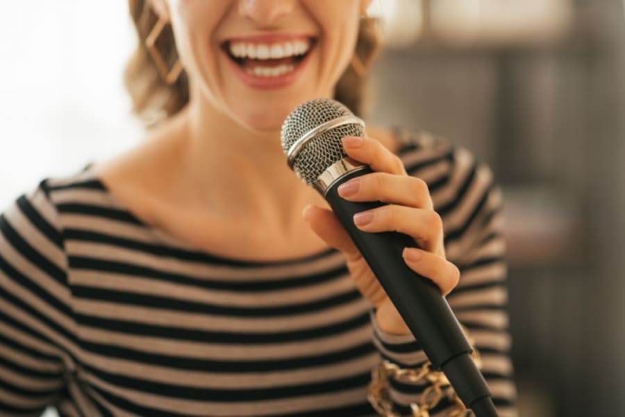 Closeup on young woman singing with microphone in loft apartment