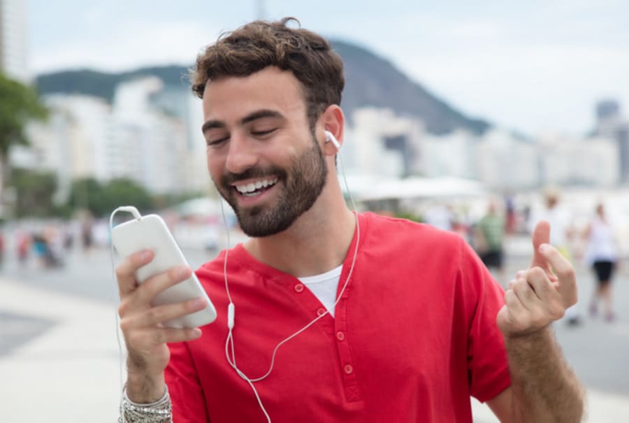 Man with red shirt and cellphone in the city listening music