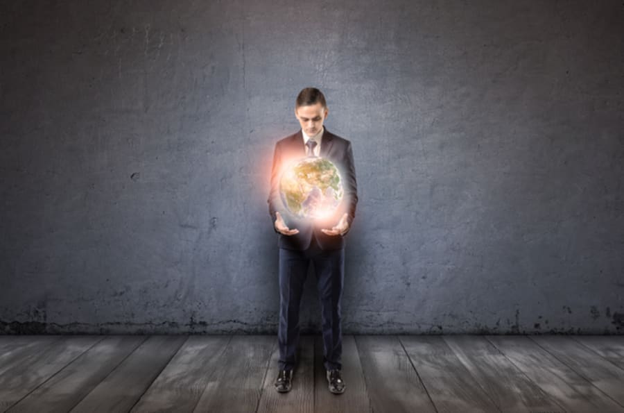 Front view of a businessman holding glowing Earth in his arms