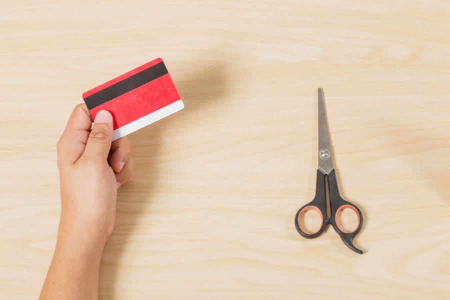 Hand holding credit card and put scissors on wood table