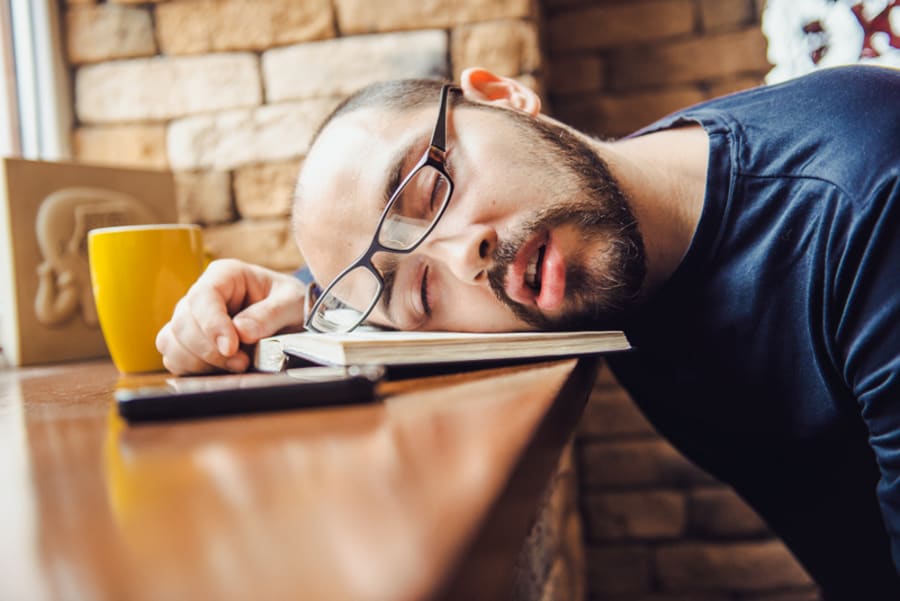 unshaven man in glasses tired, fell asleep at the table