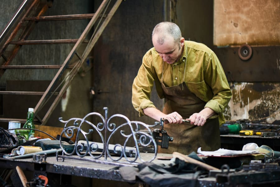 The blacksmith shapes the metal using a vise
