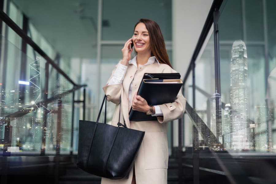 Successful businesswoman holding folders and talking on phone - double exposure