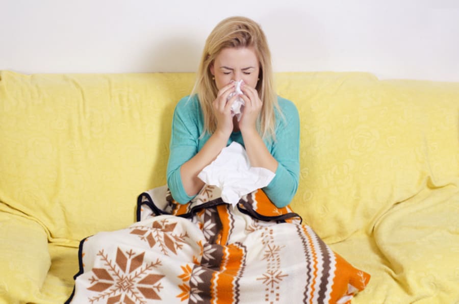 Sick young woman blowing nose at home
