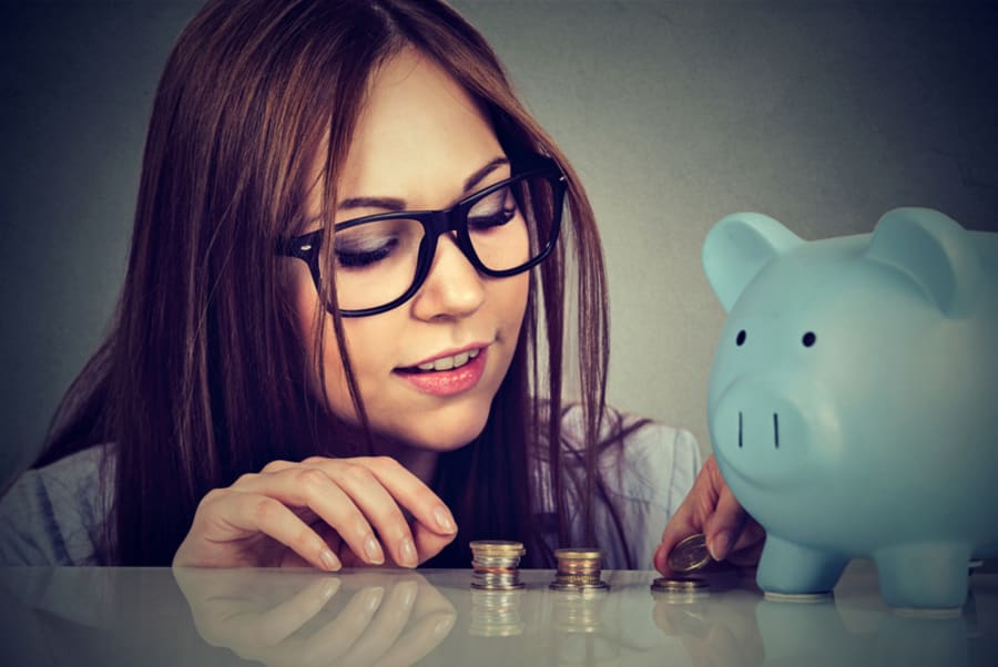 Young woman counting money stacking up coins