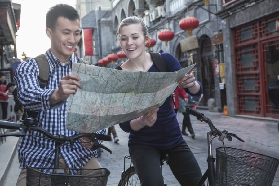Young man and woman on bicycles, looking at map.
