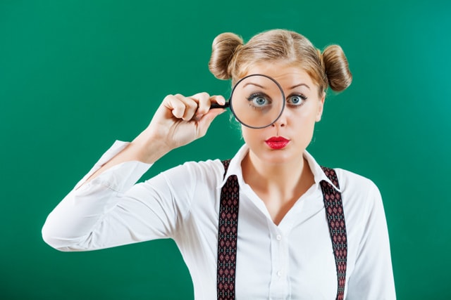Student girl with loupe in front of blackboard