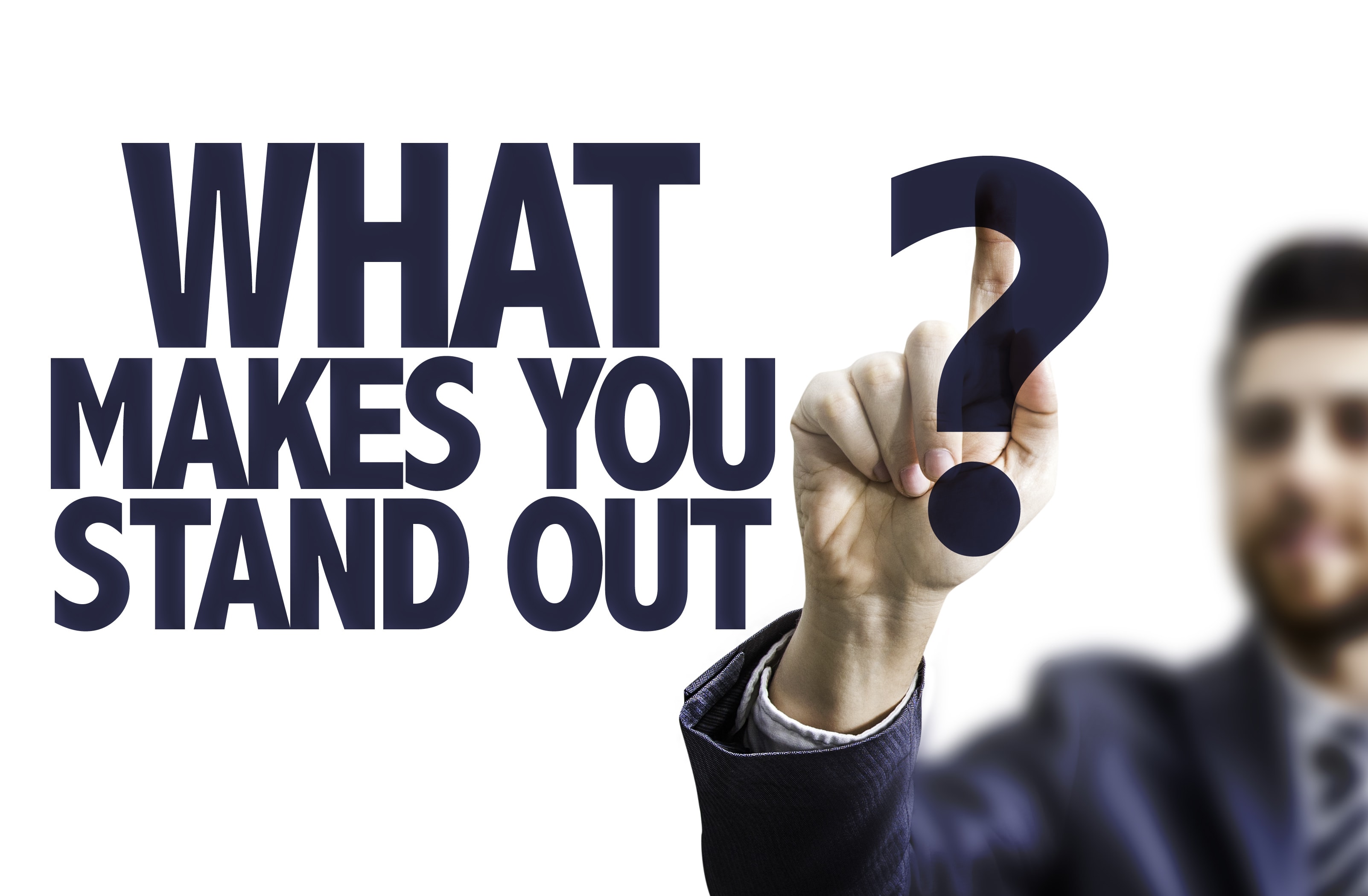 Business man pointing the text: What Makes You Stand Out?