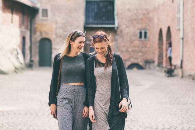 Two beautiful nordic girls  visiting old fortress in Oslo, talking and laughing. Lifestyle, tourism and friendship concepts.