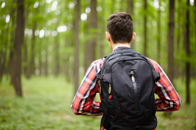 Trendy caucasian teenager boy with school bag outdoor, image from the back
