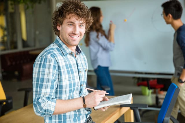 Happy smiling  man studying with students in classroom