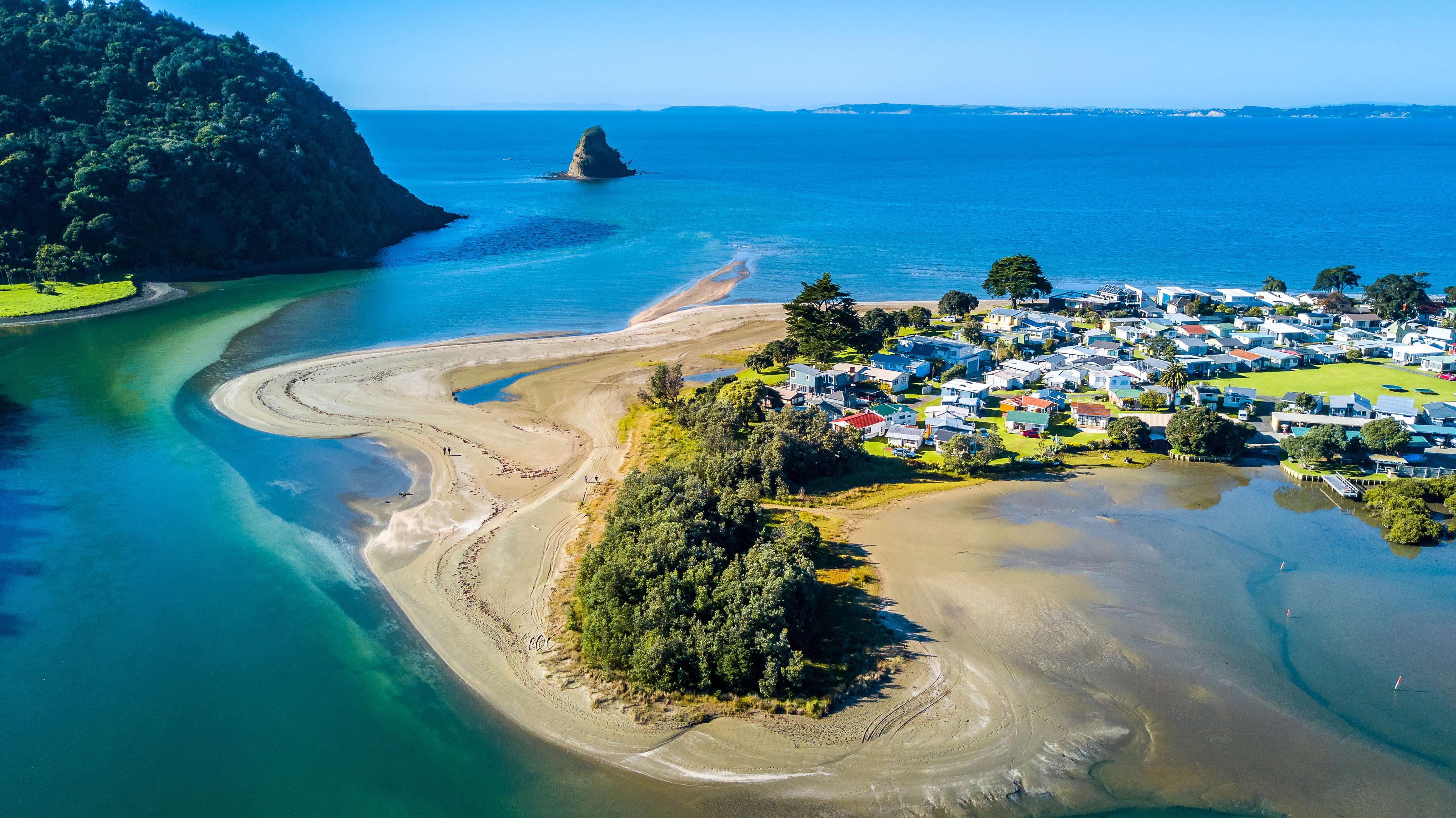 Aerial view on a river mouth with residential suburb on the shore and ocean with small islands on the background. Auckland, New Zealand