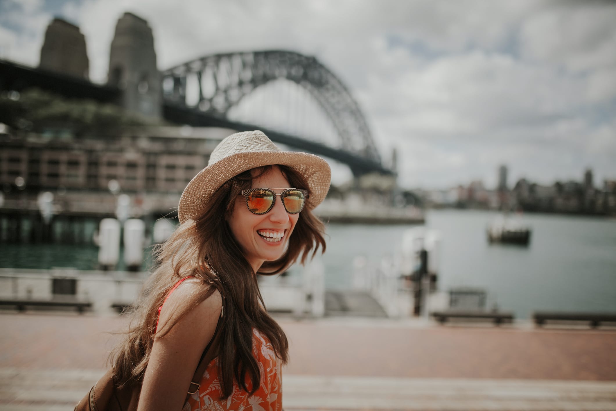 Happy smiling woman exploring Sydney, with Harbour Bridge in the background.