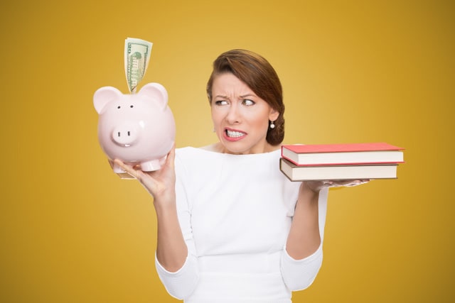 Cost of college education. Portrait stressed woman balancing piggy bank in one hand and books in another. Student having trouble paying for academic university degree tuition concept. Face expressions