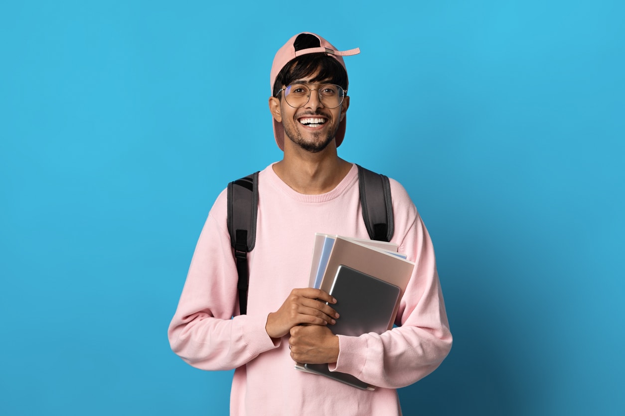 Positive indian guy student posing on blue background