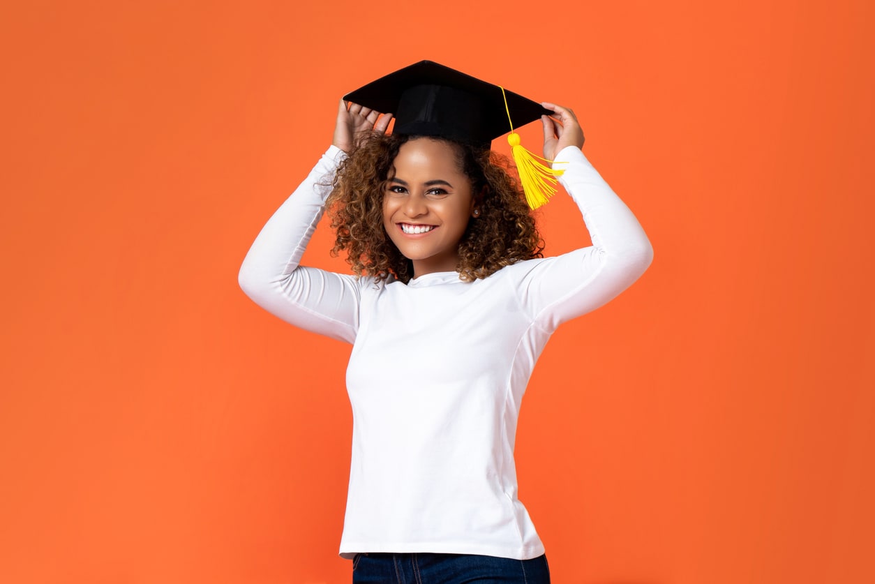Happy smiling young African American woman wearing graduation cap