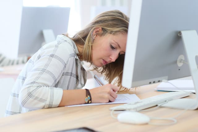 Student girl writing an exam in computers' room