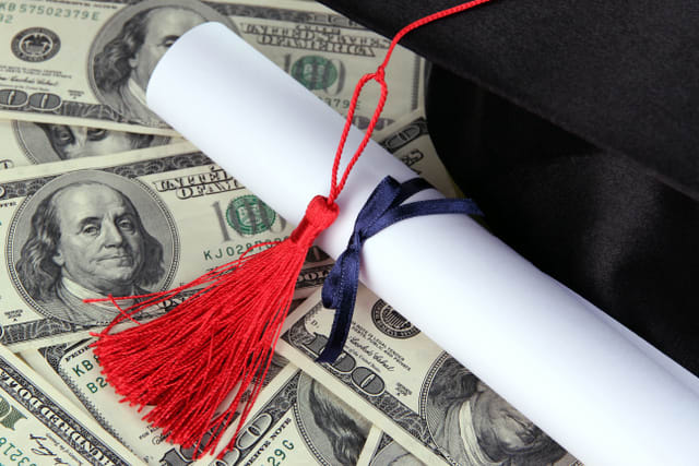 Graduation hat and scroll on money background