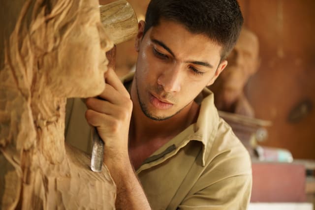 Man, people, job, young student at work learning craftsman profession in art class, working with wooden statue and carving wood