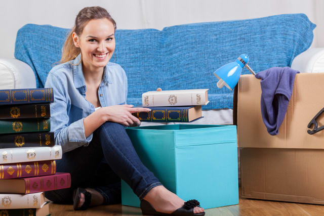 Smiling woman packing books during moving house