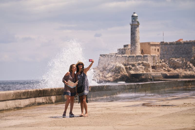 Female friends on holiday, people traveling, young women having fun for vacations, happy girls smiling in Havana, Cuba. Persons taking selfie with camera phone, smartphone, mobile telephone picture