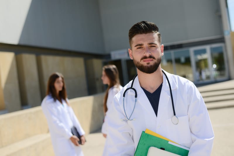 portrait of handsome young man medical student outdoor in front of hospital university campus