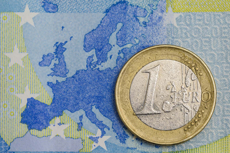 Detailed close up of an one euro coin on a blue twenty euro bank